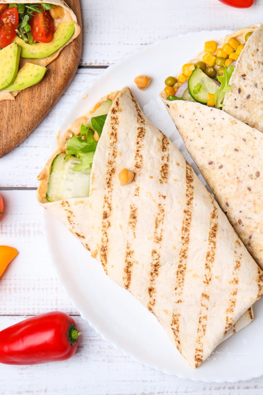 Plate with Hummus Wraps and Vegetables on White Wooden Table