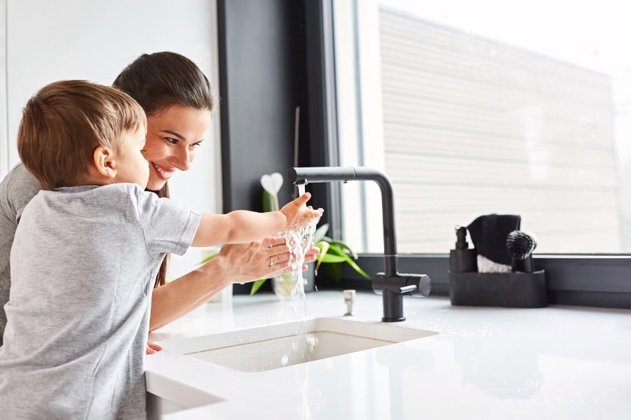 mom and young son washing hands together