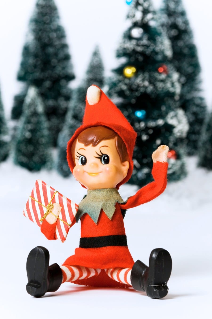 Vintage Christmas Elf holding a present in one hand and waving with the other