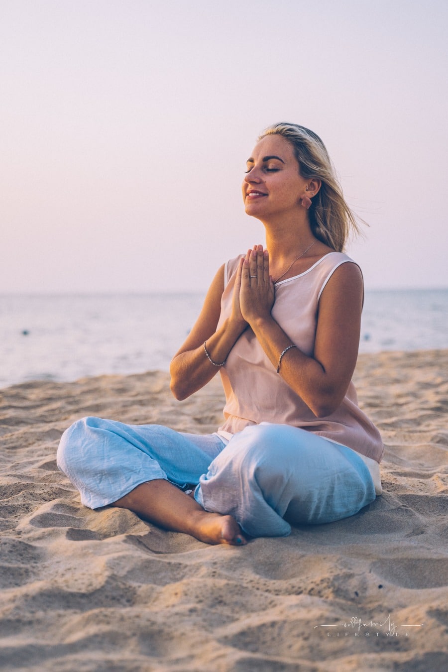 woman praticing mindfulness through yoga on a beach