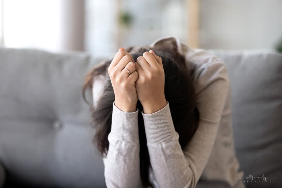 depressed woman on couch with her head in her hands