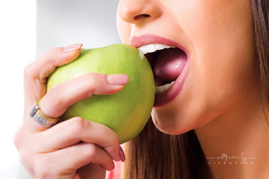 Young woman perfect teeth bites apple