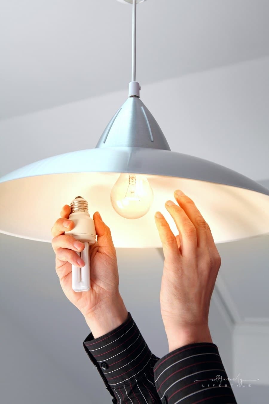 person changing bulbs to fluorescent to save energy
