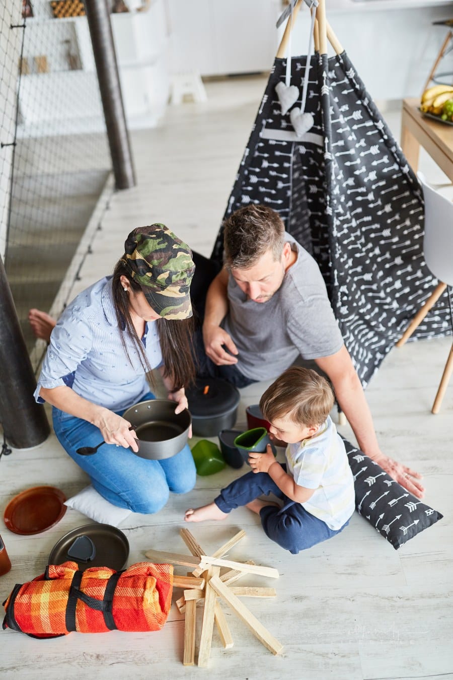 Family with child playing in tent camping and camping at home in living room