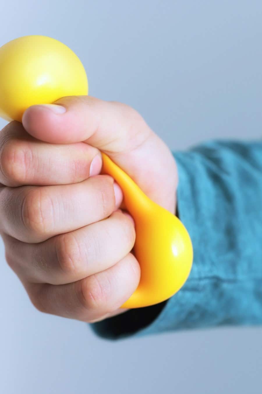 Man squeezing antistress ball on grey background, closeup