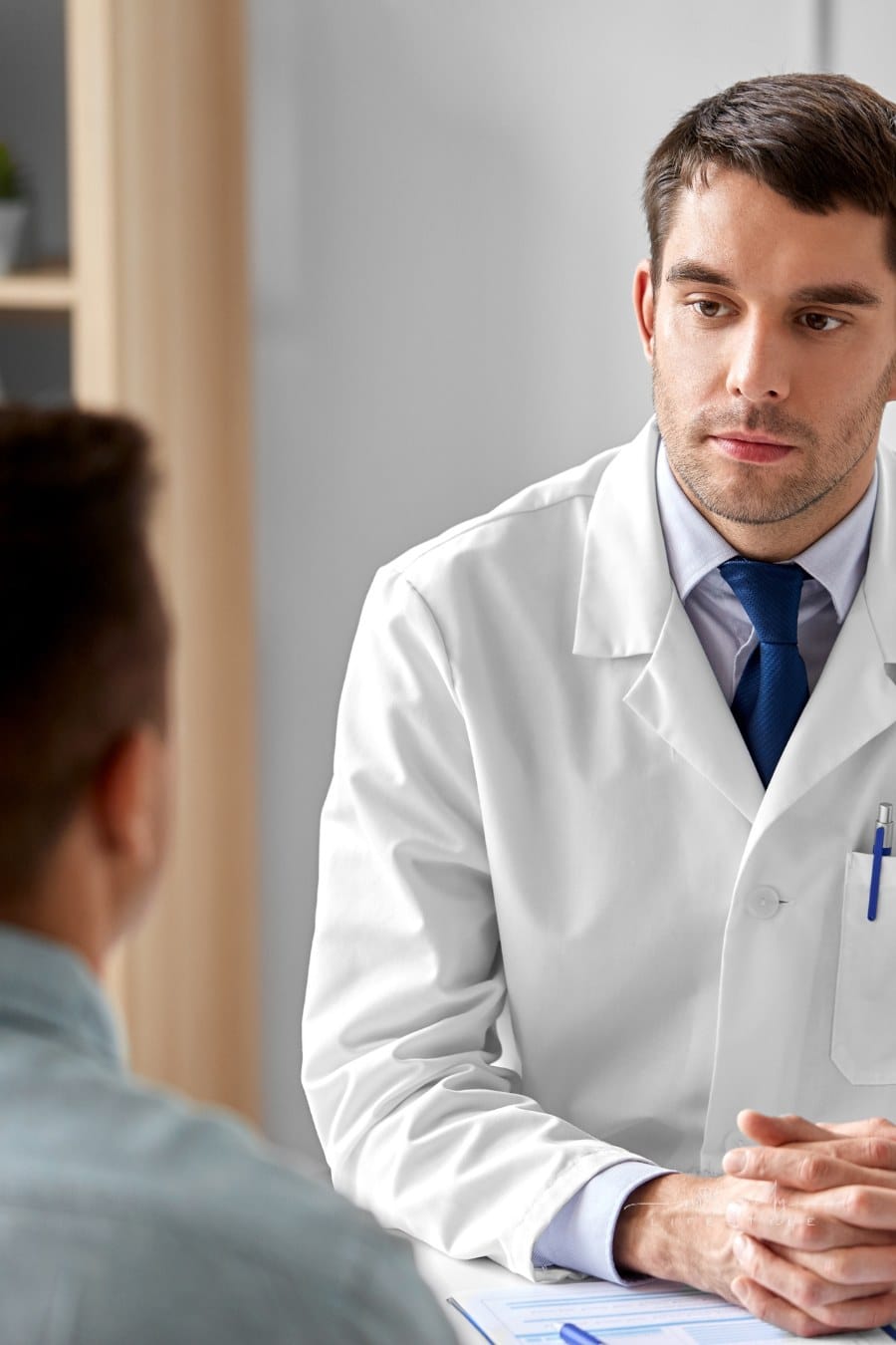 Doctor Listening to Male Patient at Hospital