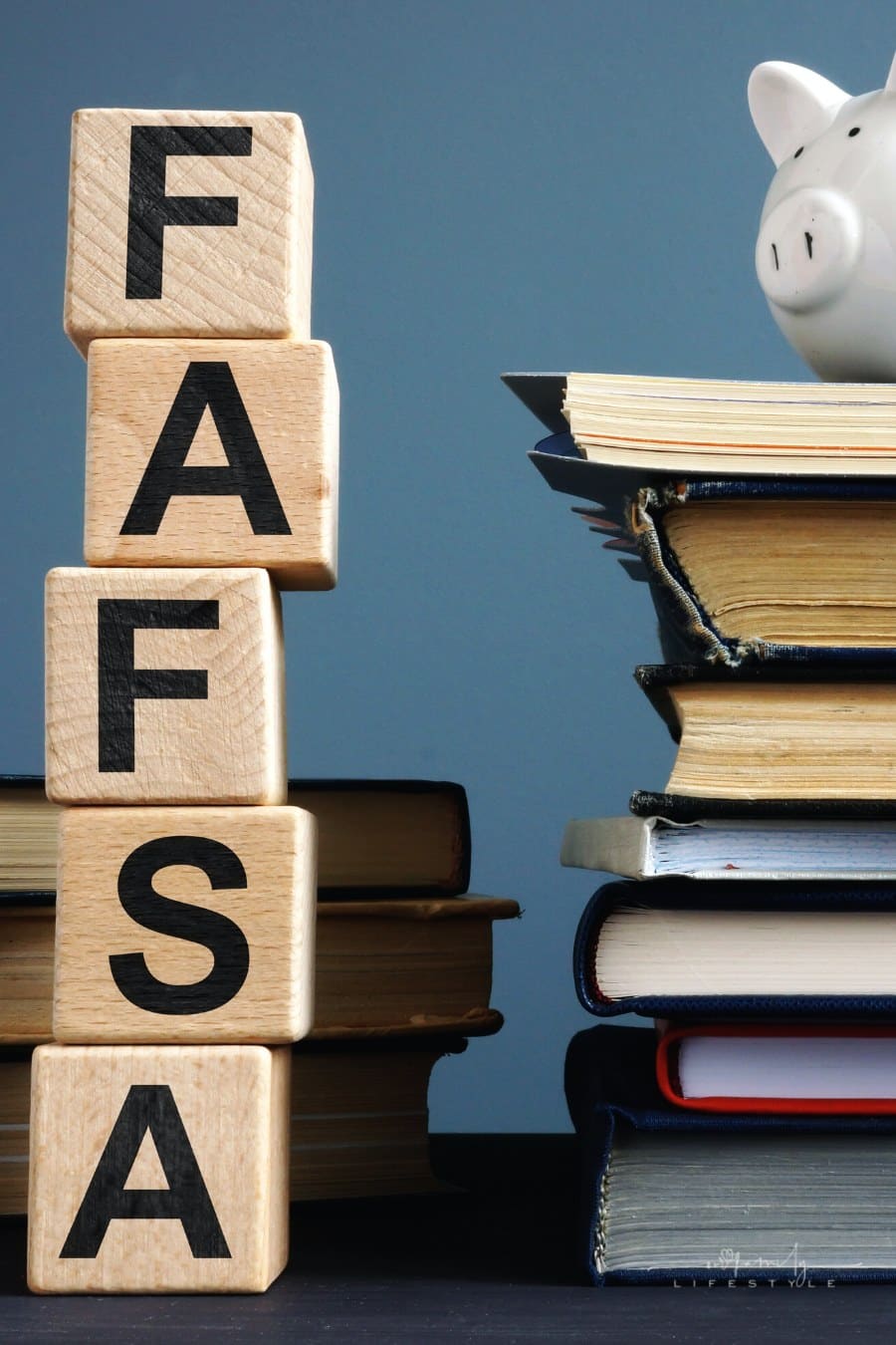FAFSA free application for federal student aid concept with letter blocks next to stack of books with piggy bank on top