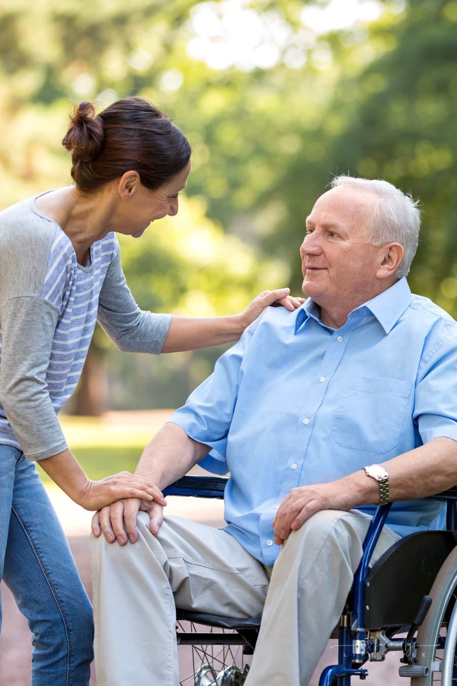adult daughter talking to aging father in wheelchair