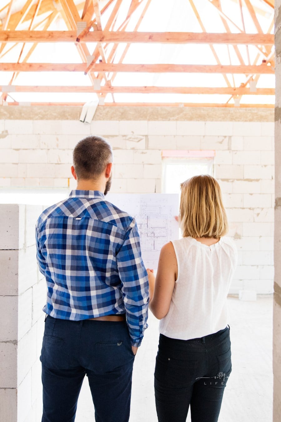 Young Couple looking at blueprints at Construction Site of new home