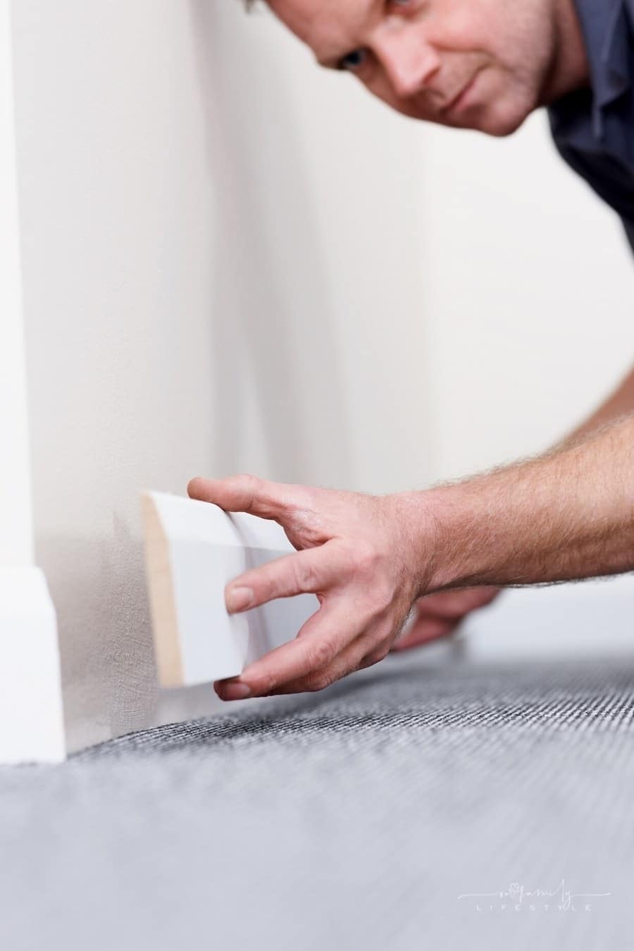 contractor fitting skirting board onto bottom of wall