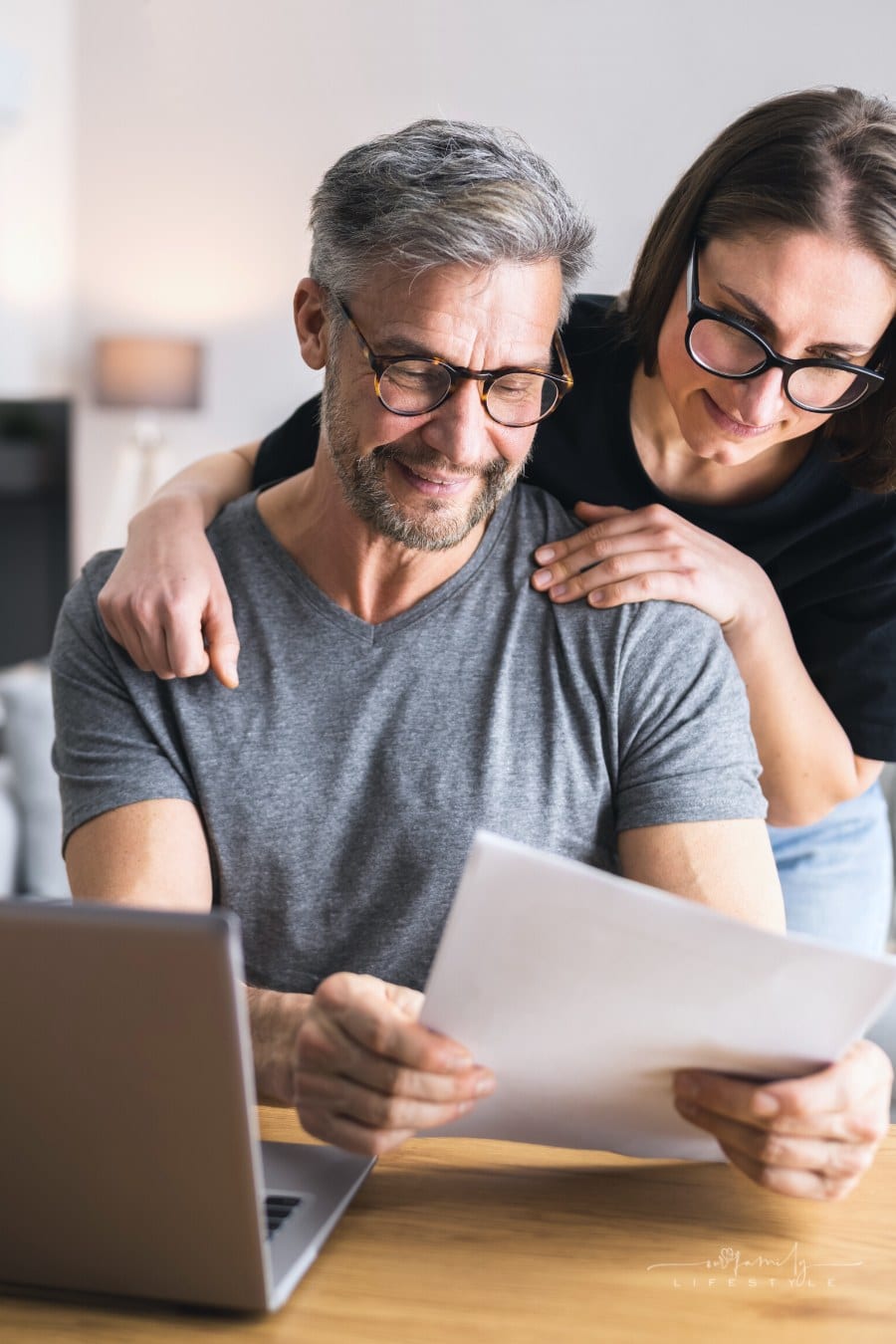 couple smiling in front of laptop while going over family budget