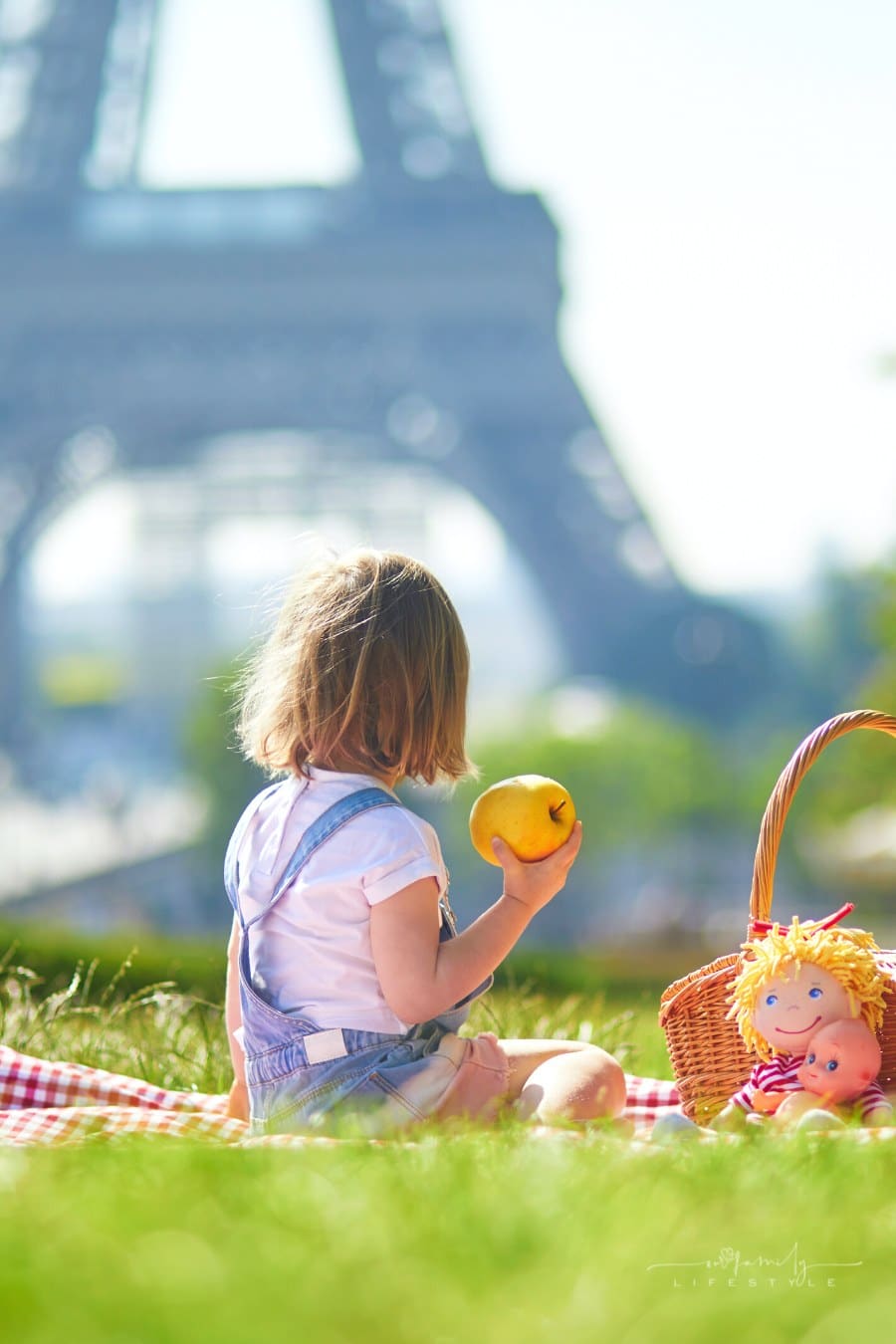toddler having a picnic with her doll near the Eiffel Tower in Paris, France