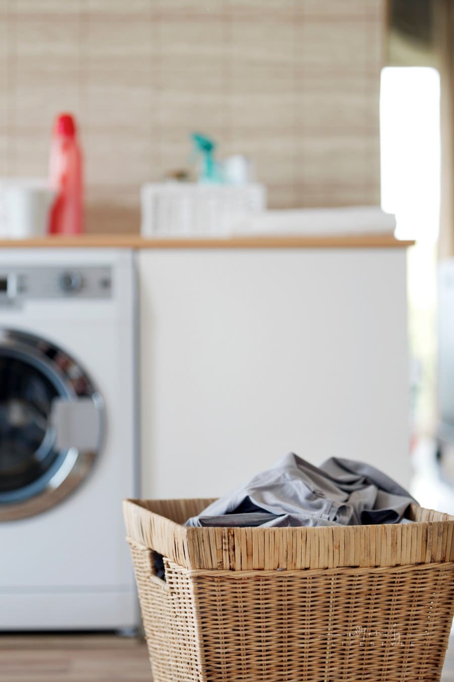 laundry basket filled with dark clothes with washing machine in background
