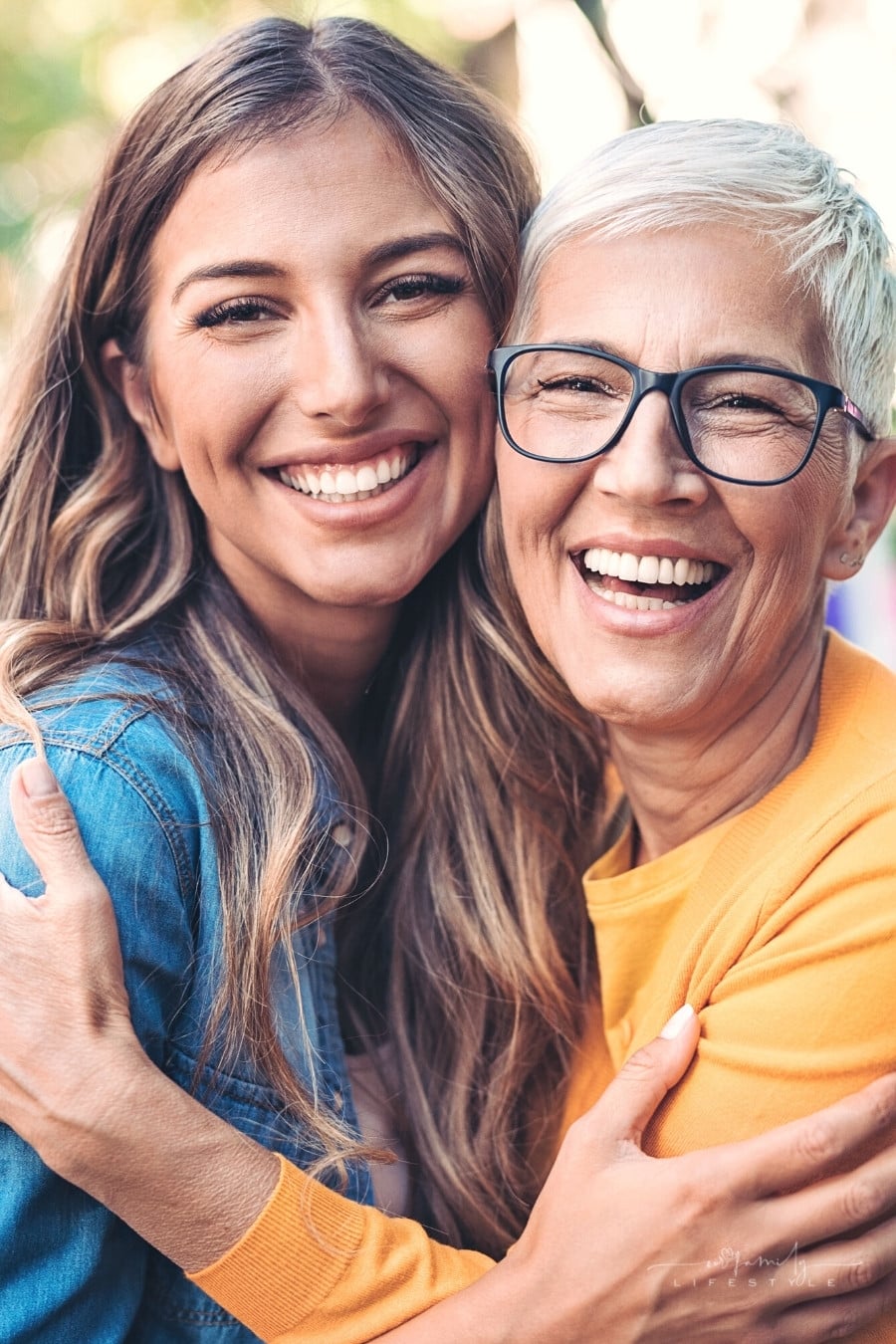 adult daughter hugging mature mom with short gray hair and black-rimmed glasses