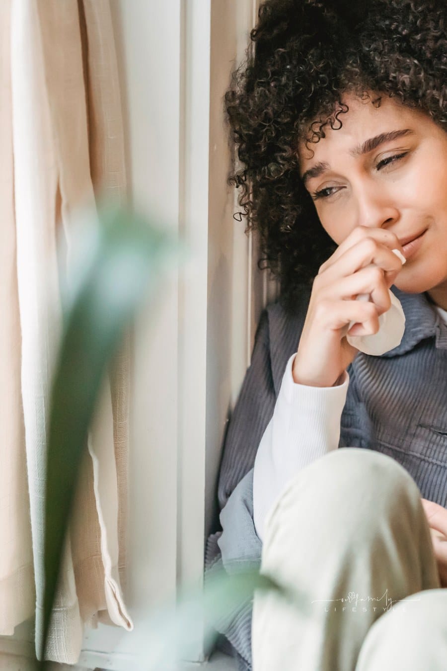 depressed woman sitting near window with box of tissues