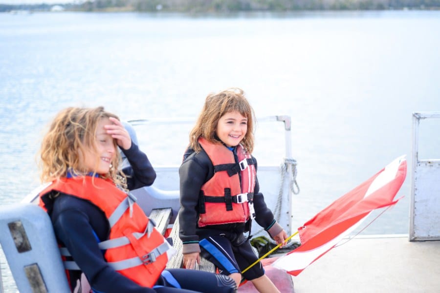 Two cute little kids on a boat wearing life jackets in a candid photograph. Fun on the water
