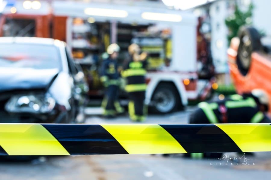 road closed with caution tape after an accident; emergency vehicles on accident site