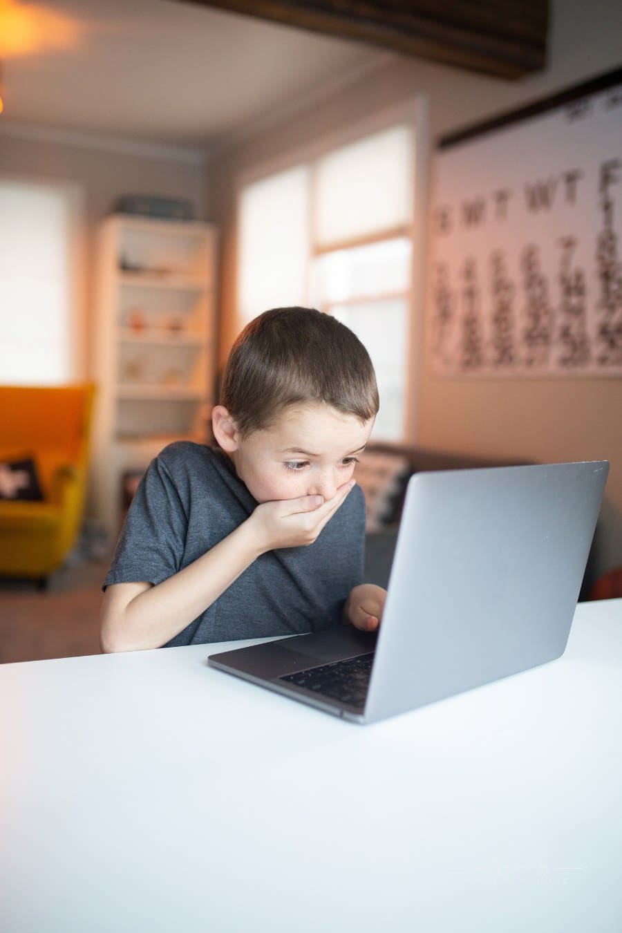 boy covering his mouth in awe while looking at laptop