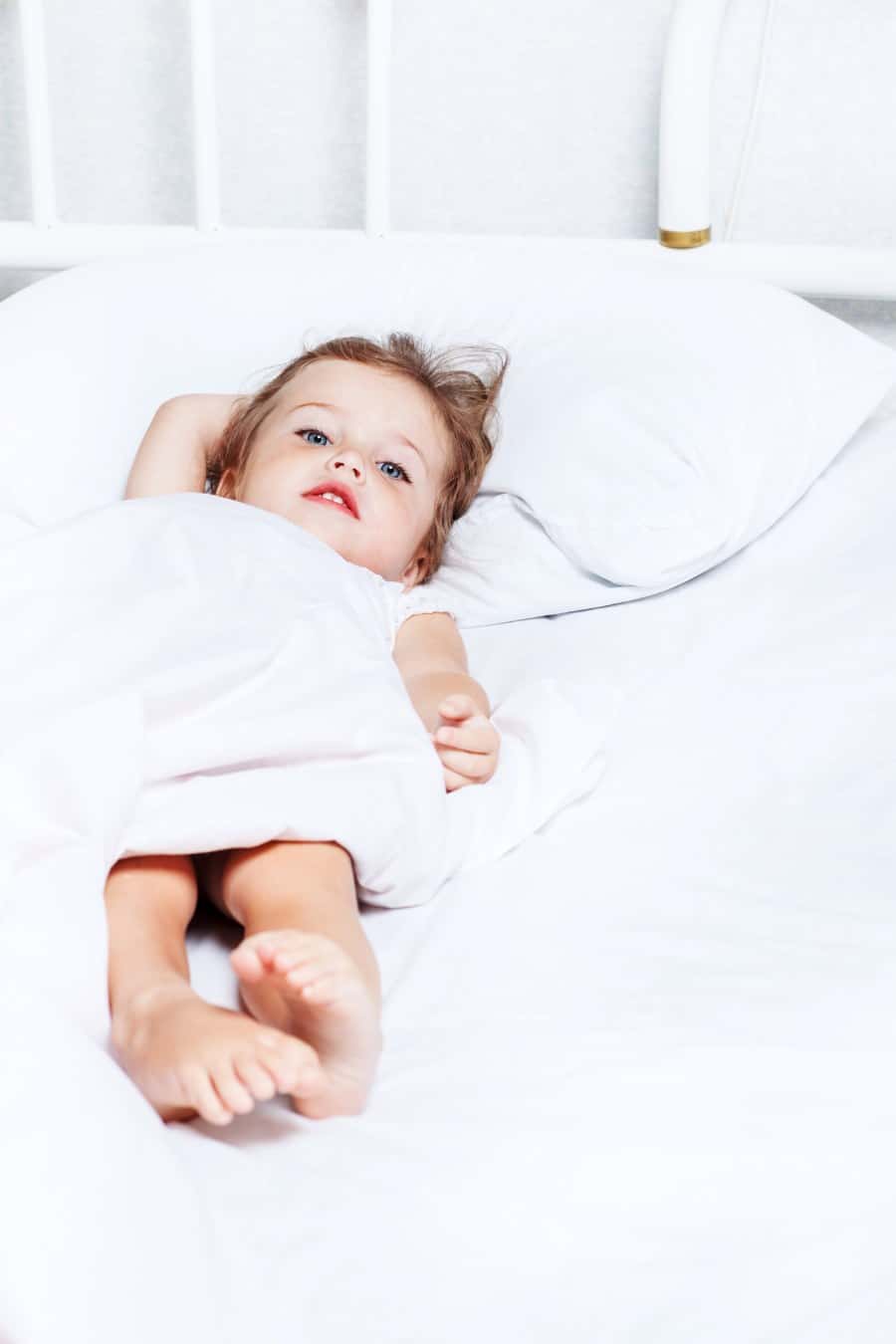 toddler stretching out on bed