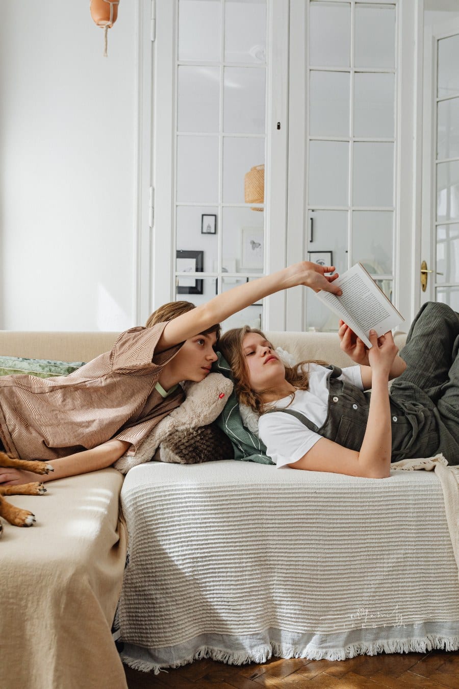 Siblings Lying on the Couch with a book