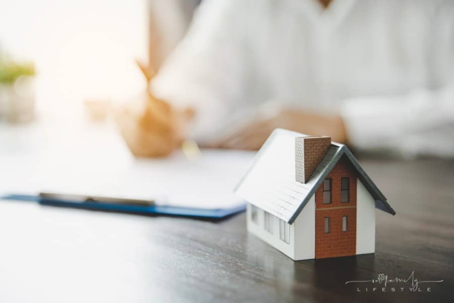 signing residential rental lease with small house figure in forefront