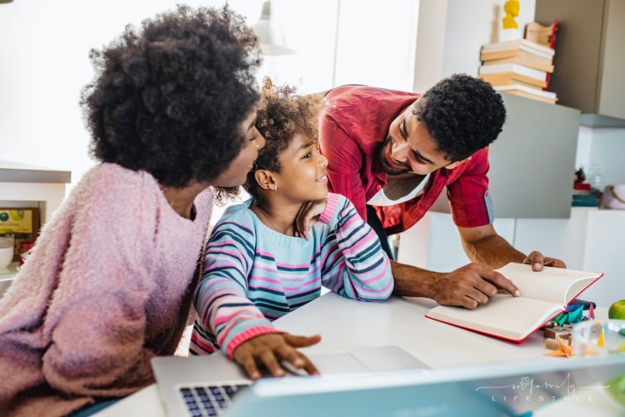 mom and dad helping child learn with laptop at home