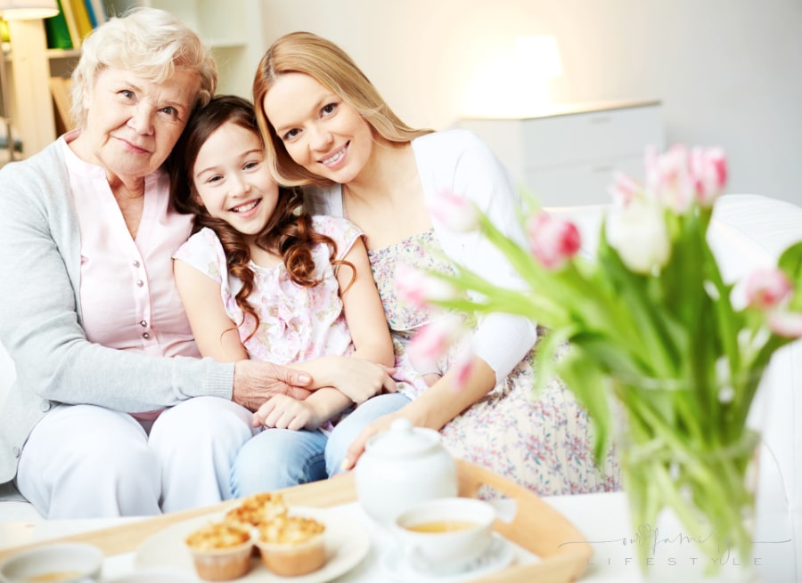 Portrait of happy little girl, her mother and grandmother looking at camera at home