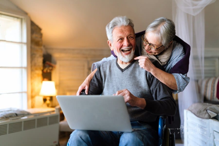 Happy senior couple using notebook at home and having fun together. Technology people concept
