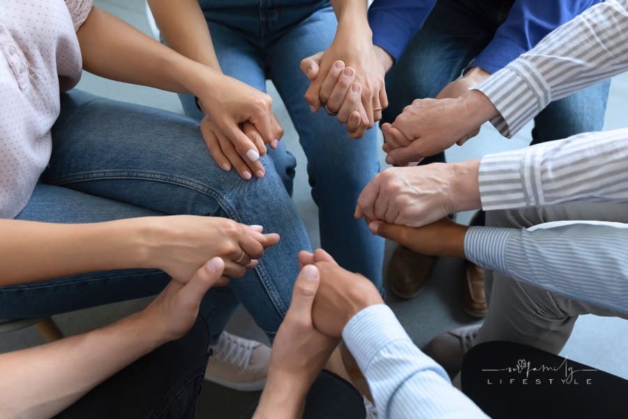 Group of anonymous people holding hands in a circle during group therapy