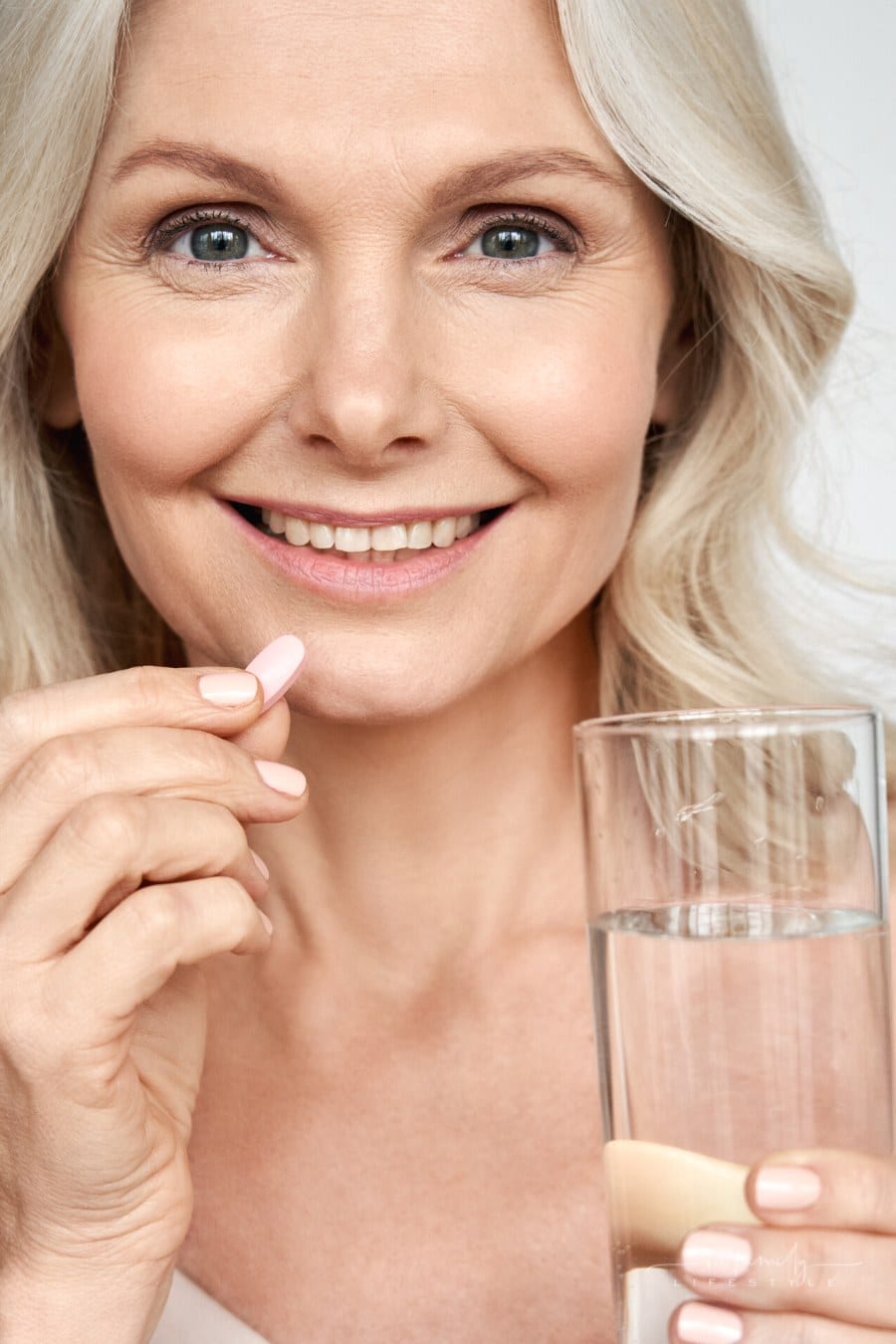 middle aged woman taking a supplement with water