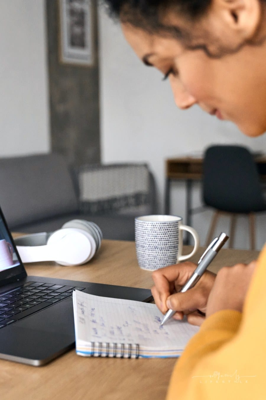 female college student taking notes with laptop in front of her