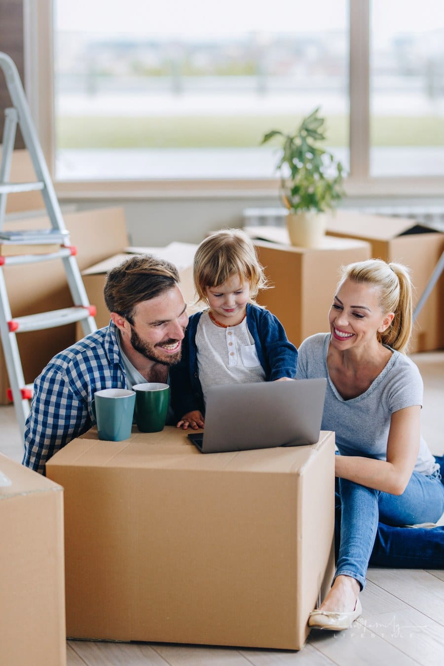 parents planning move on laptop sitting moving boxes with young son nearby