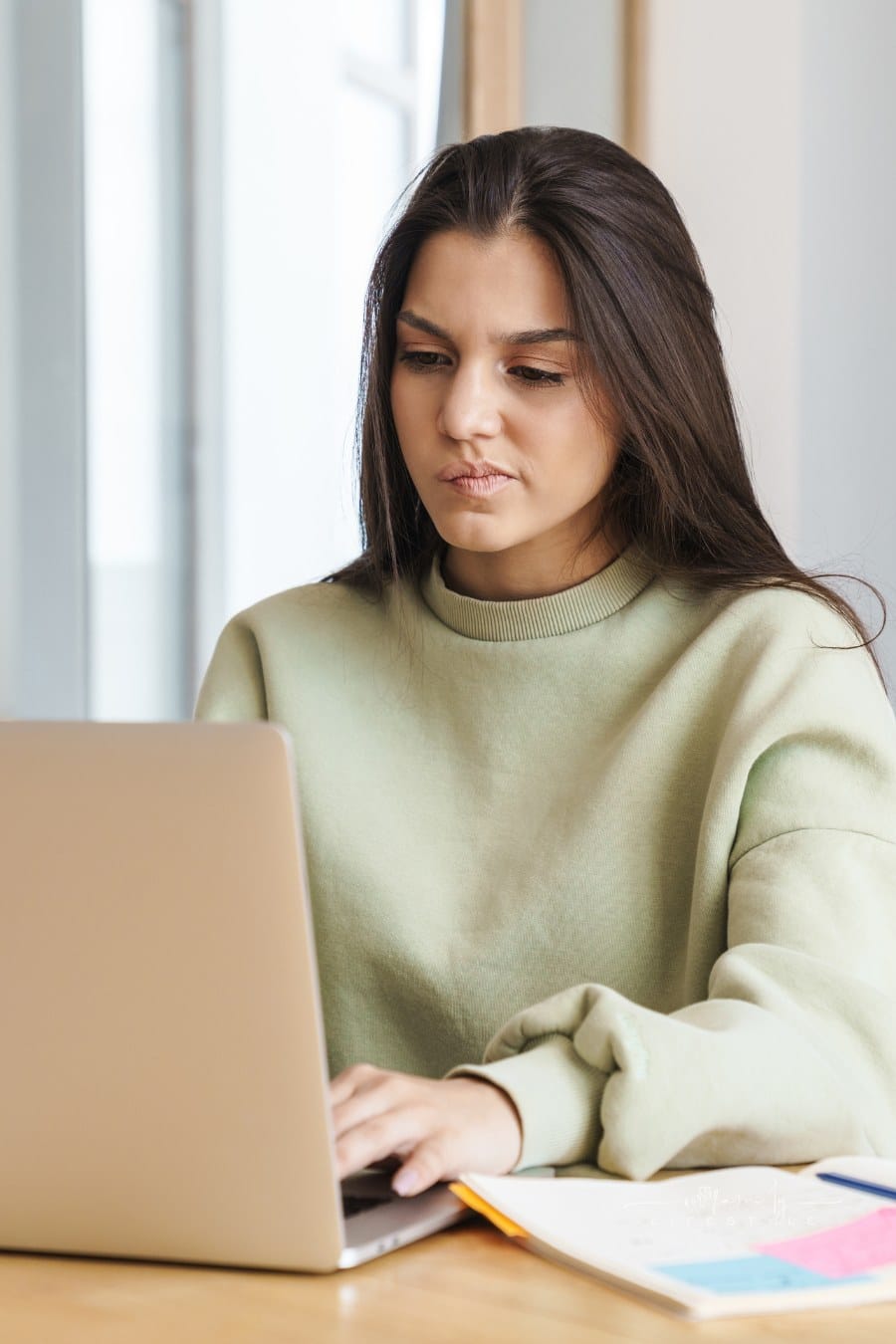Perplexed College Student Using Laptop While Doing Homework