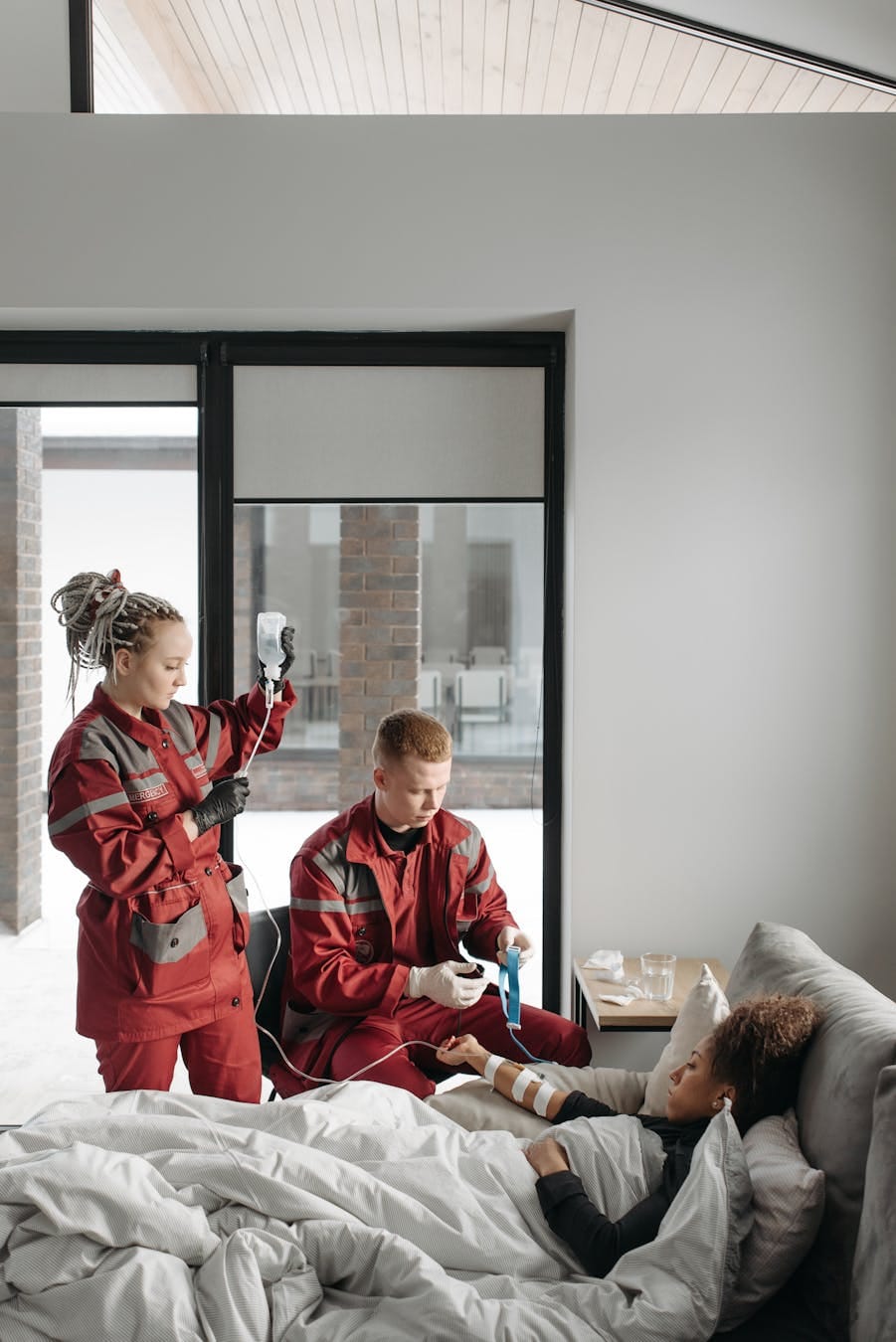 Paramedics provide care to a patient in a bright home setting, offering medical assistance.