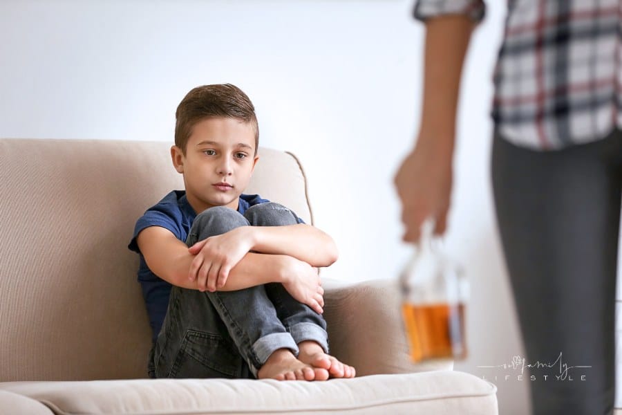 Sad Little Boy and Blurred Parent with Bottle of Alcohol