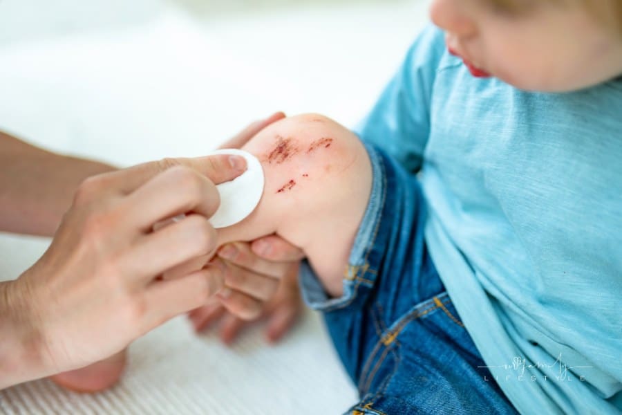 Toddler Boy with Scraped Knees. Parent Helping Her Child Perform First Aid Knee Injury after an Accident.