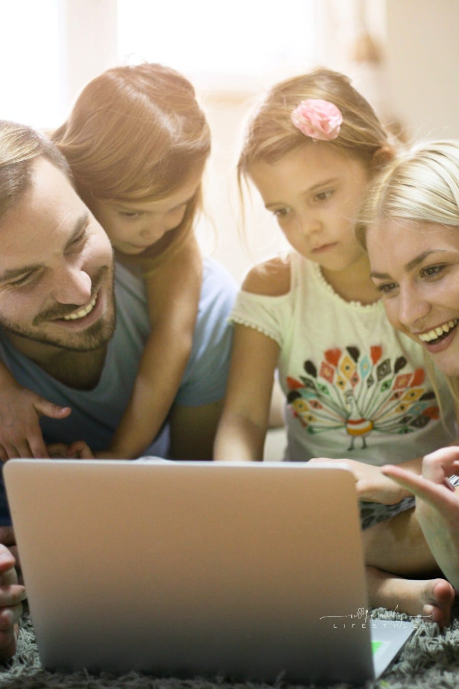 mom and dad looking at laptop with daughters