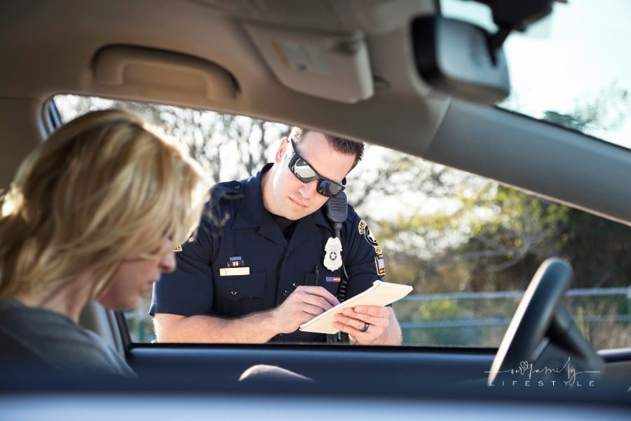 Police officer writing ticket at car window