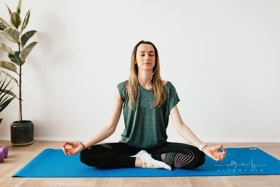 Peaceful lady sitting in Padmasana pose while meditating on mat