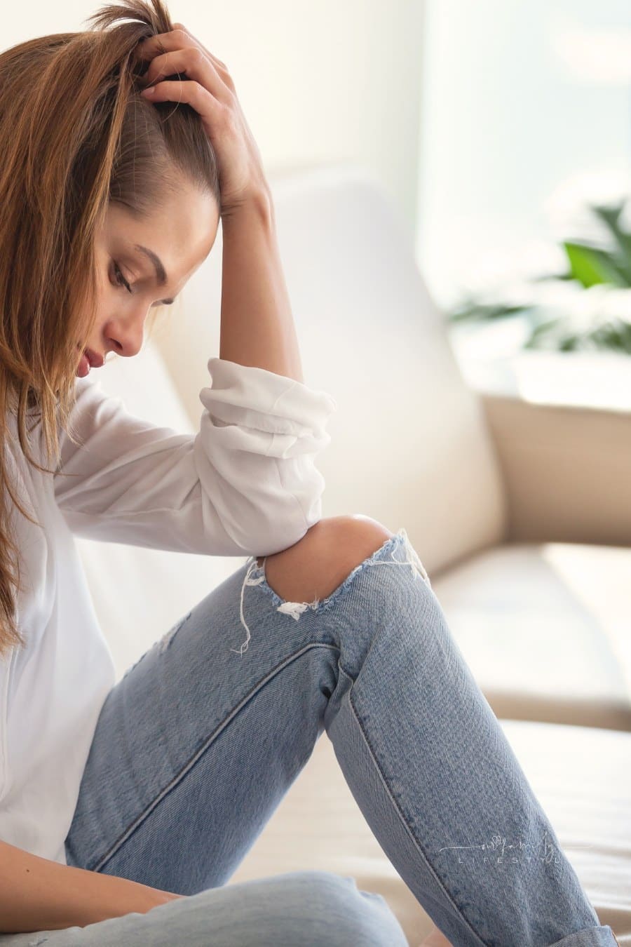 Sad depressed woman feeling bad at home sitting on sofa
