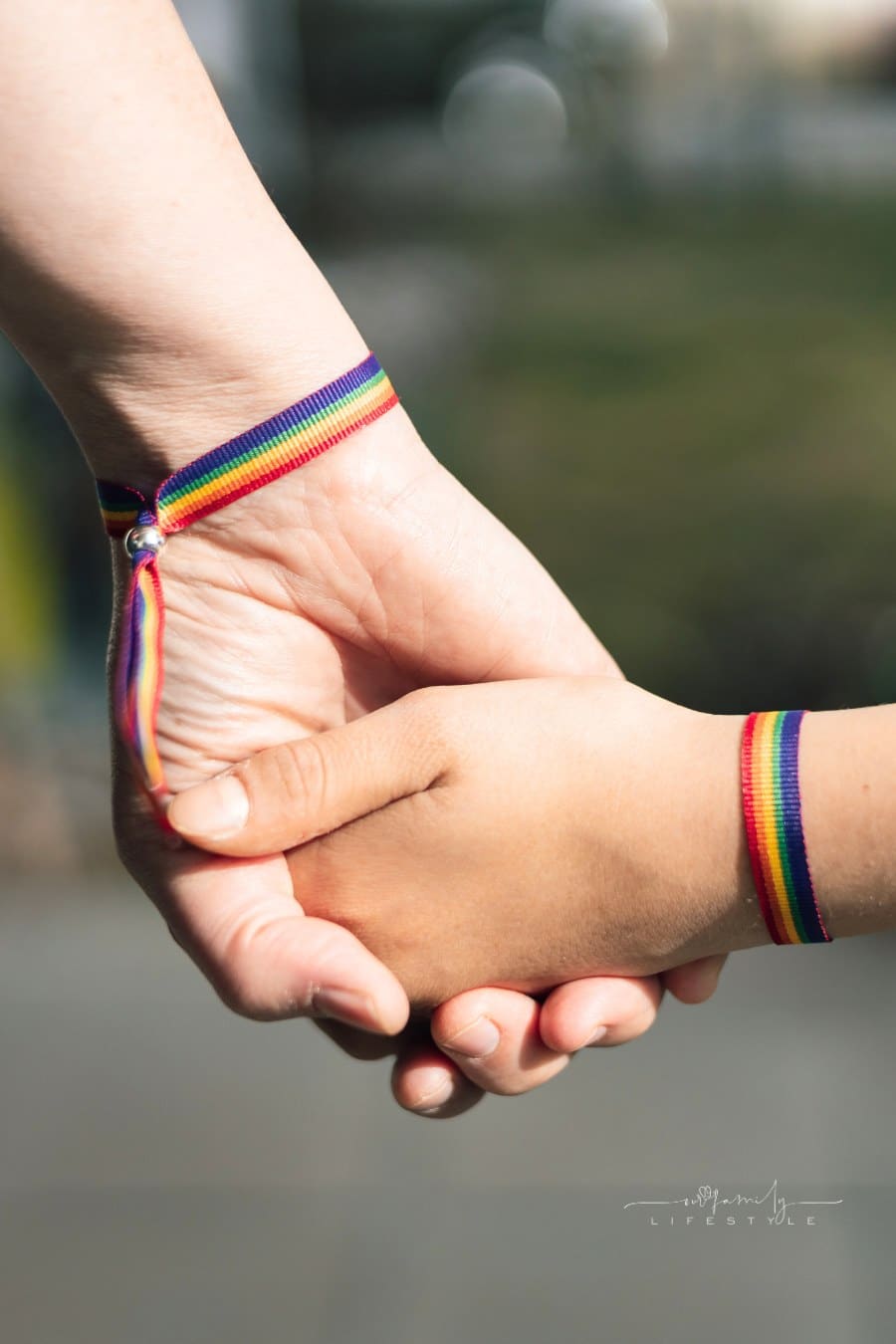 Mother and daughter holding hands with a rainbow-bracelet