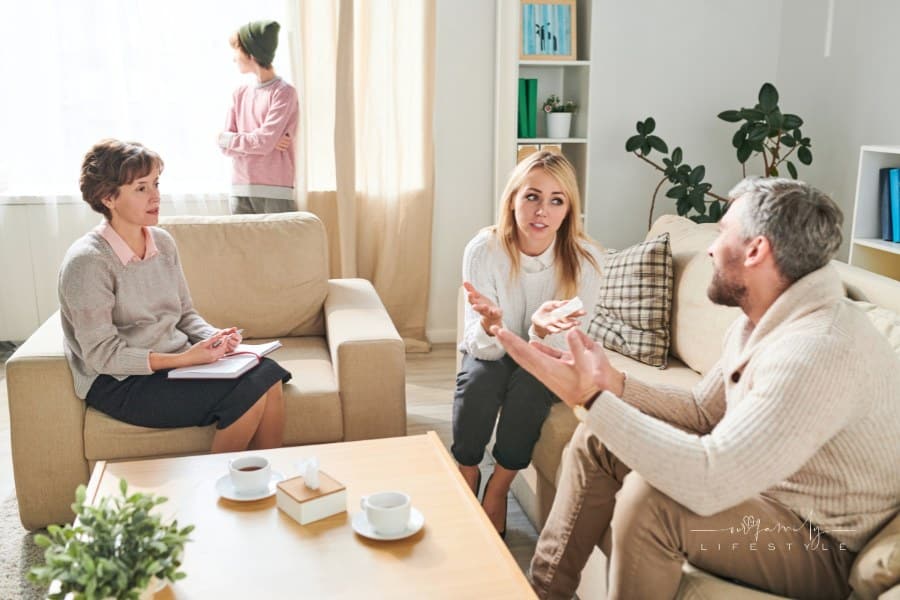 Parents discussing their problems with psychologist: mother gesturing hands while explaining her suffering to husband while l