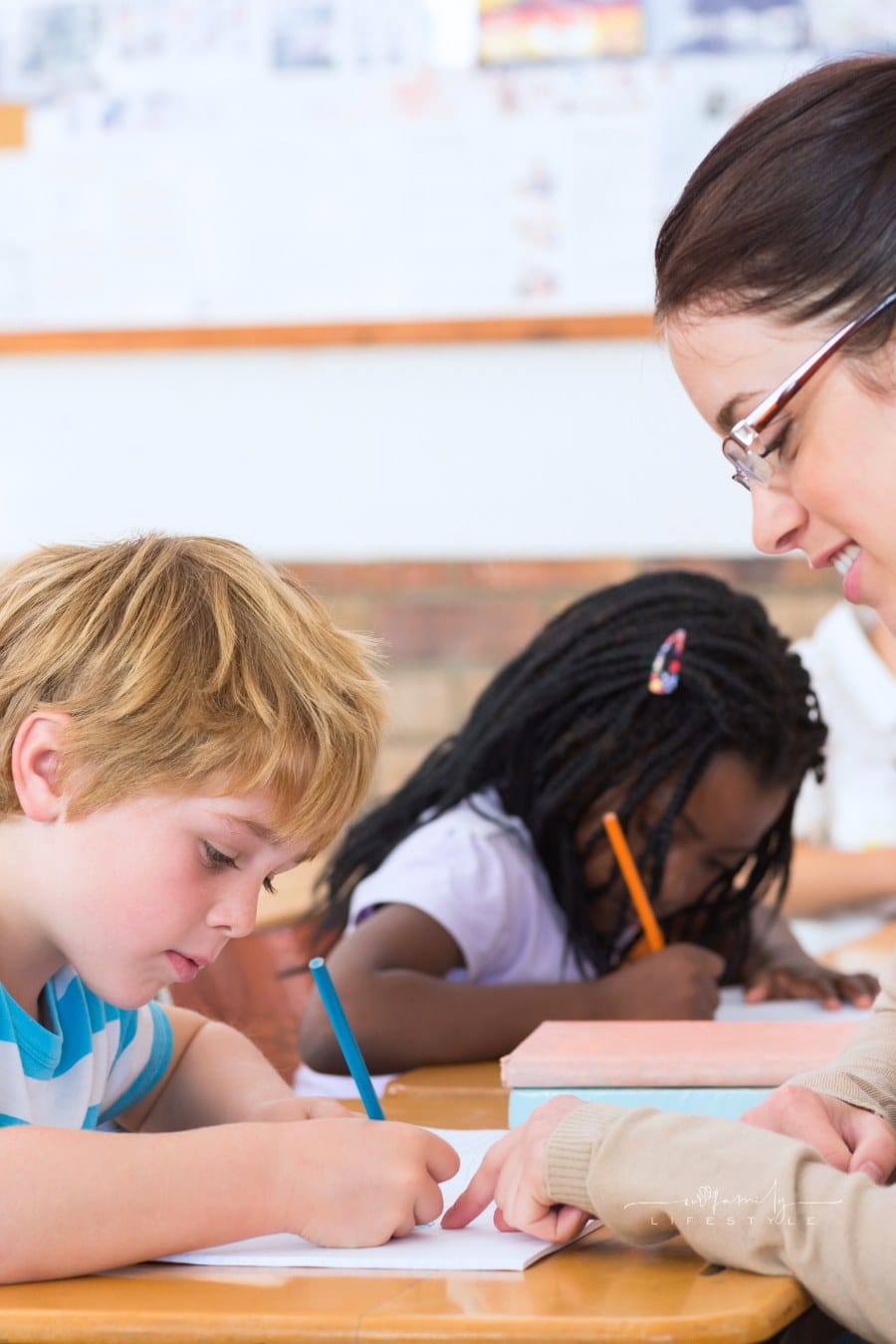 teacher helping young student in the classroom
