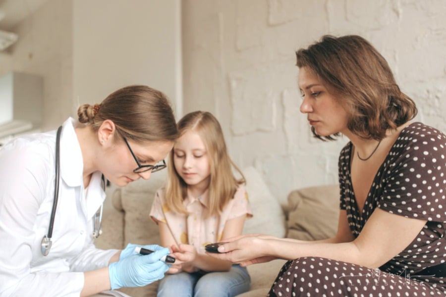 pediatrician checking blood sugar of patient with mom looking on