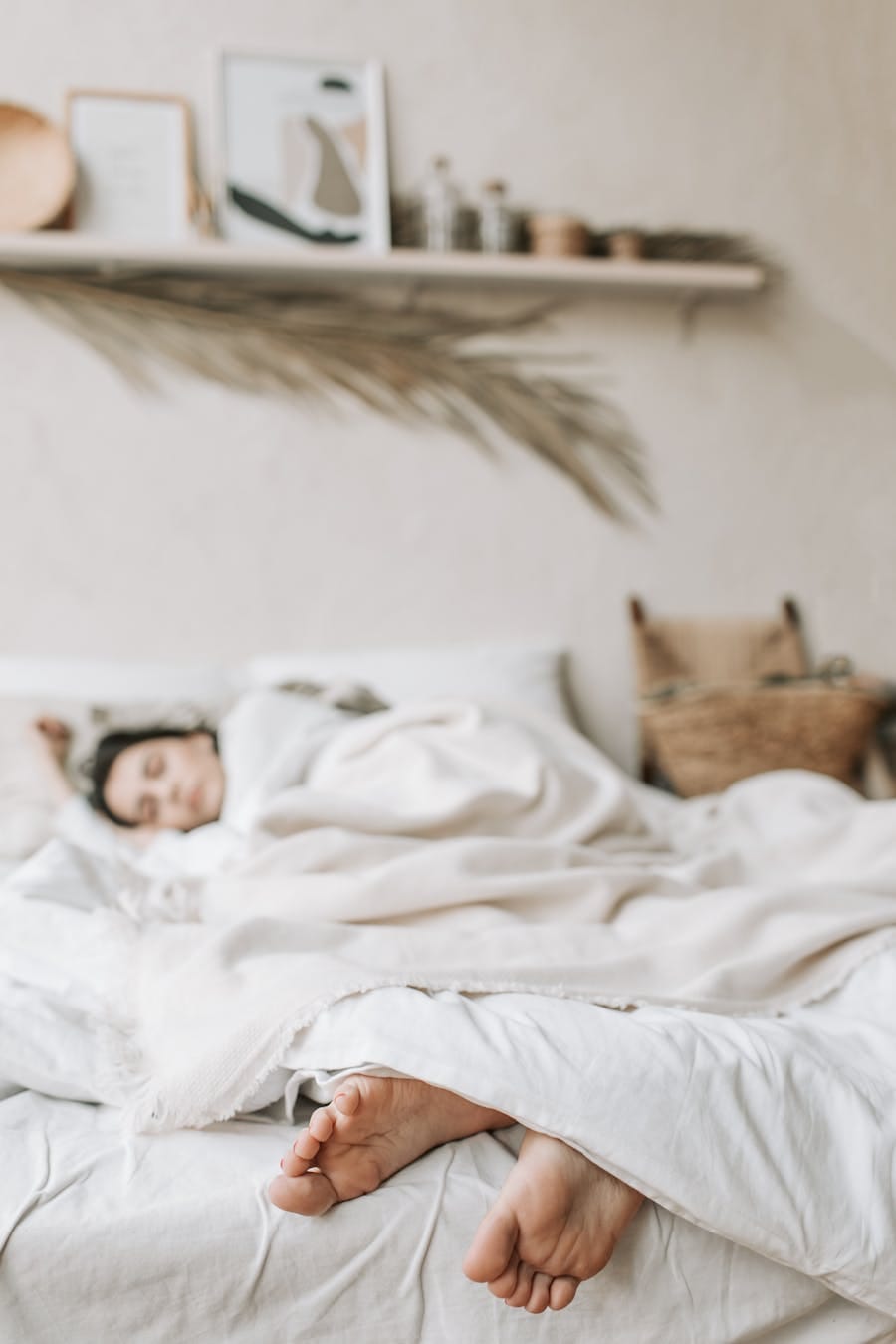 Relaxing indoor scene of a woman sleeping under a soft blanket in a cozy room.
