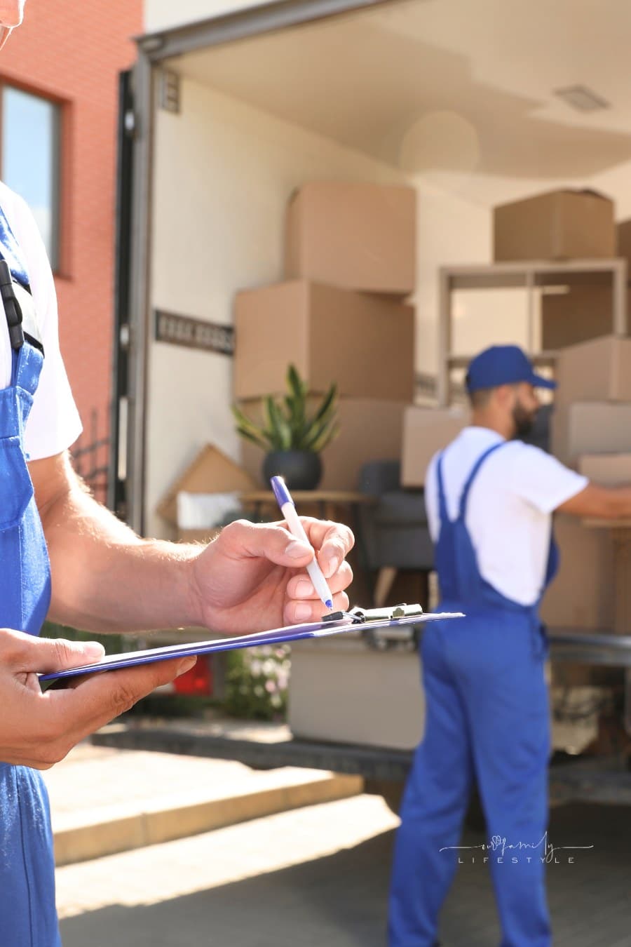 two men loading a moving truck and checking items off a list