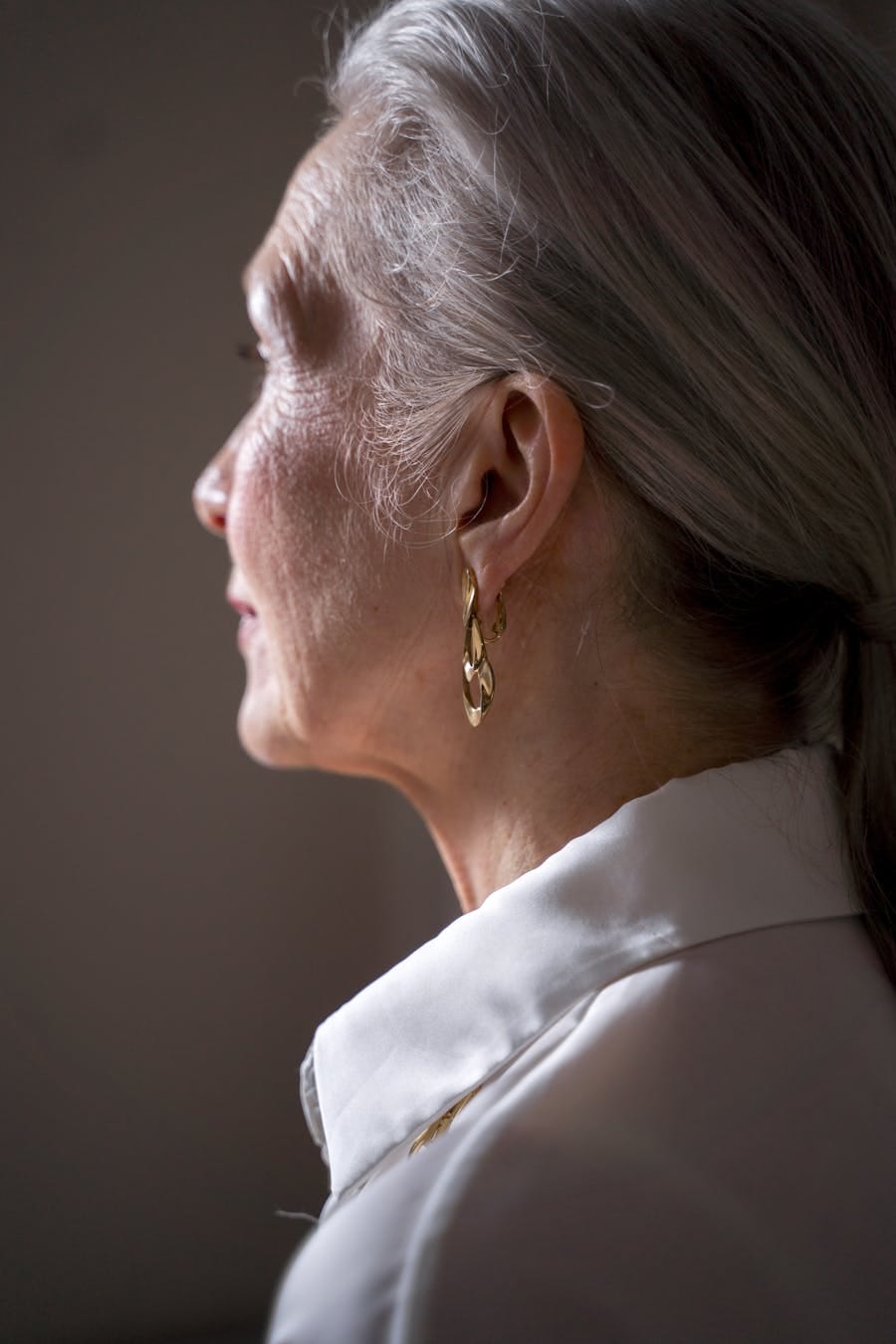 Side profile of a senior woman showcasing elegance and golden earrings.
