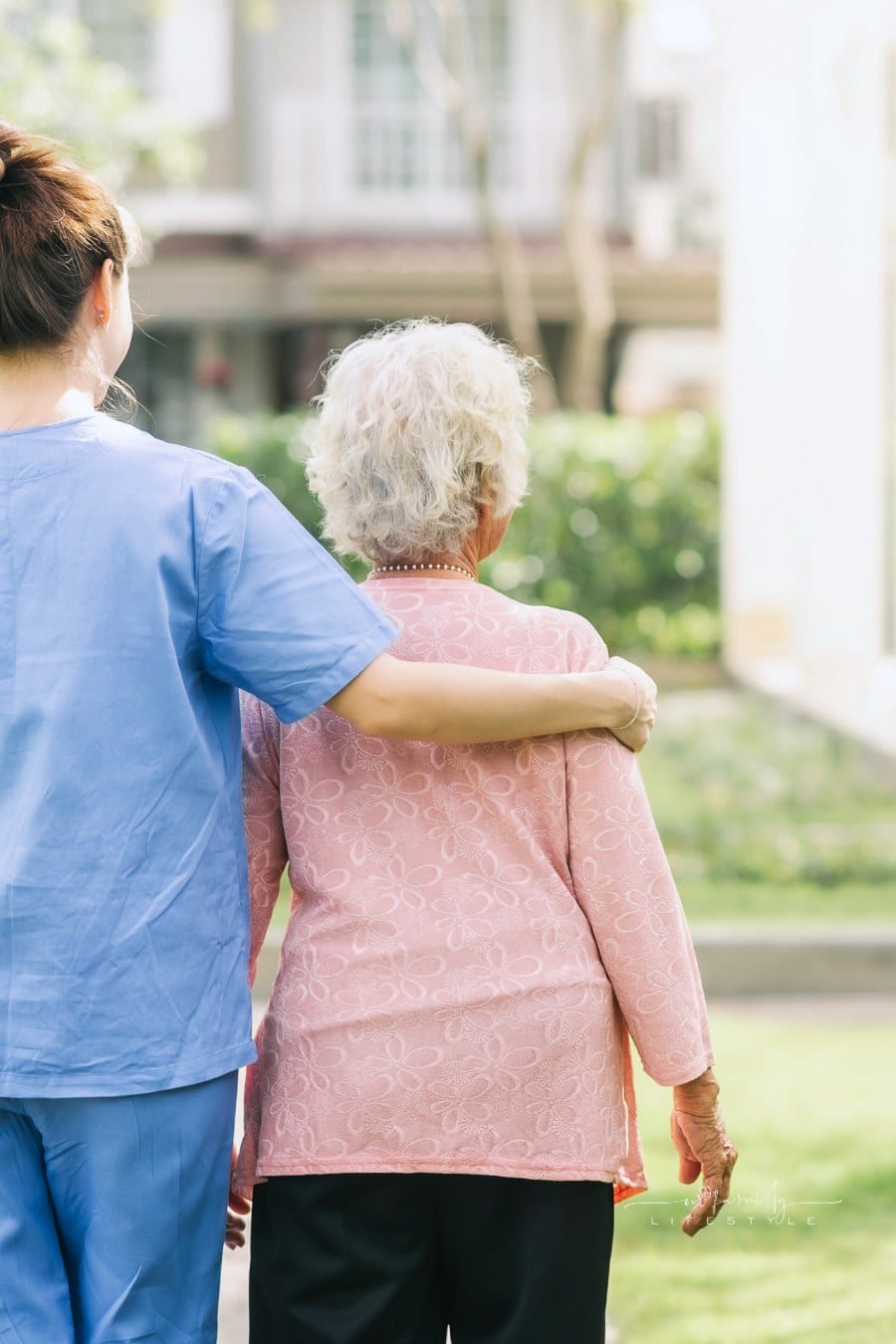 Caregiver Supporting an Elderly Woman as They Walk