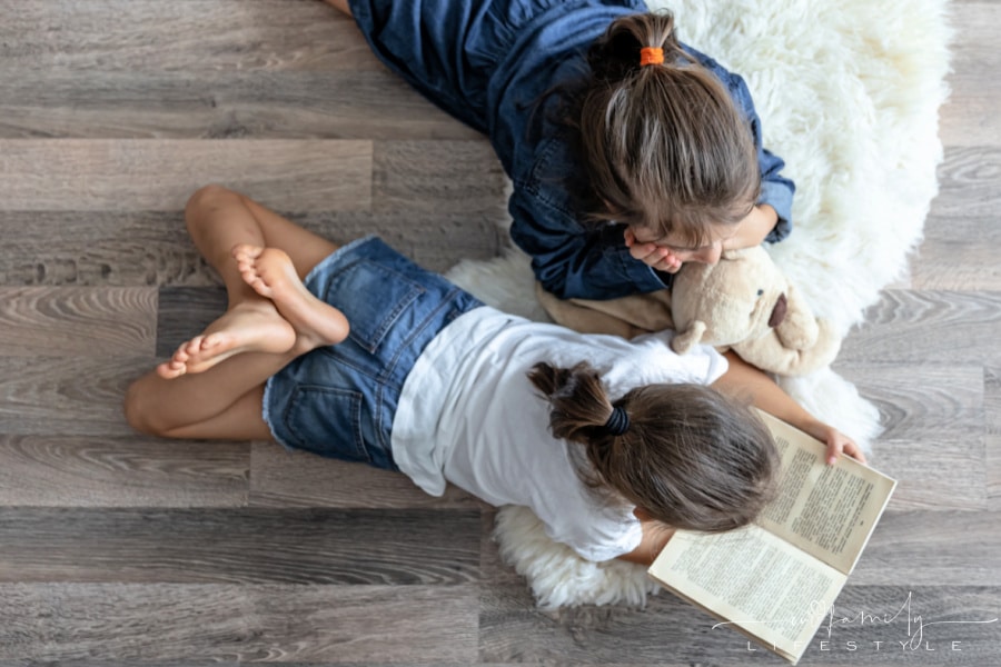 sisters-reading-book-with-teddy-bear-lying-floor
