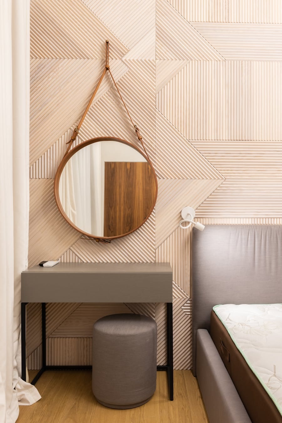 Sleek and stylish bedroom interior featuring a geometric wall pattern with a round mirror.